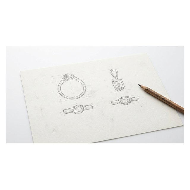 Pencil sketches of a ring and pendant with construction lines on white artist's paper