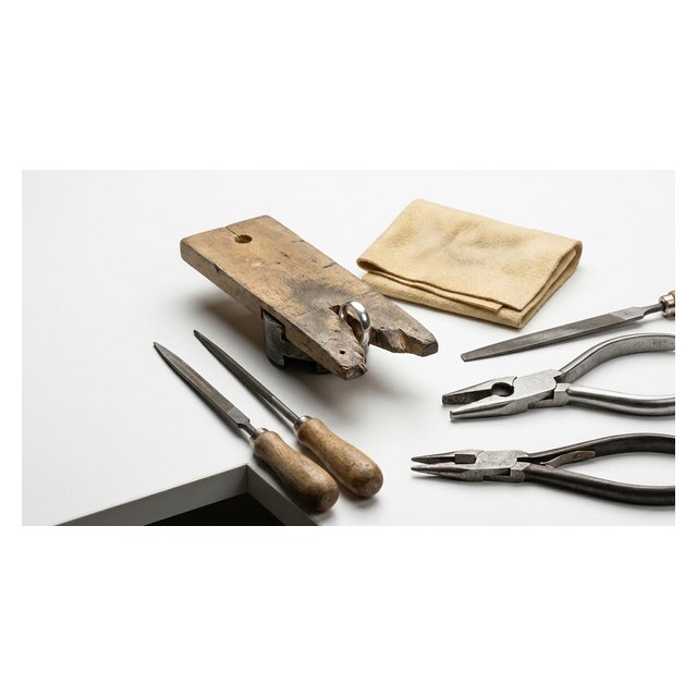 A bench jeweller's essentials: bench pin, hand vice with silver ring, files and pliers